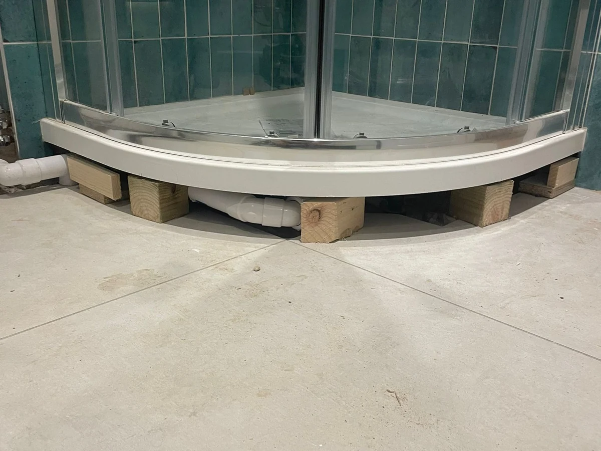 Quadrant shower tray on packing blocks during bathroom installation in Swansea