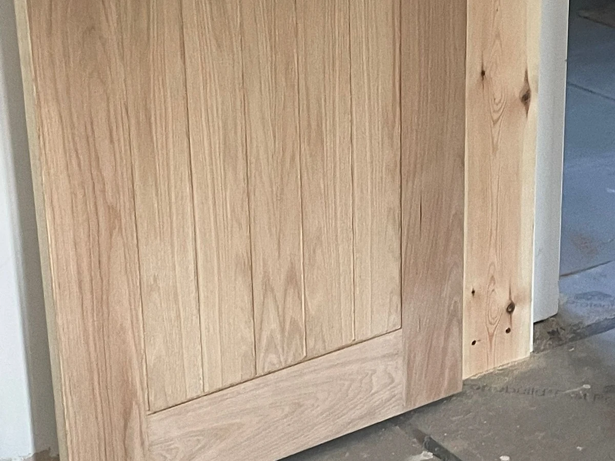 Unfinished solid oak shaker panel internal door being fitted during renovation in Swansea by Daffodil Carpentry