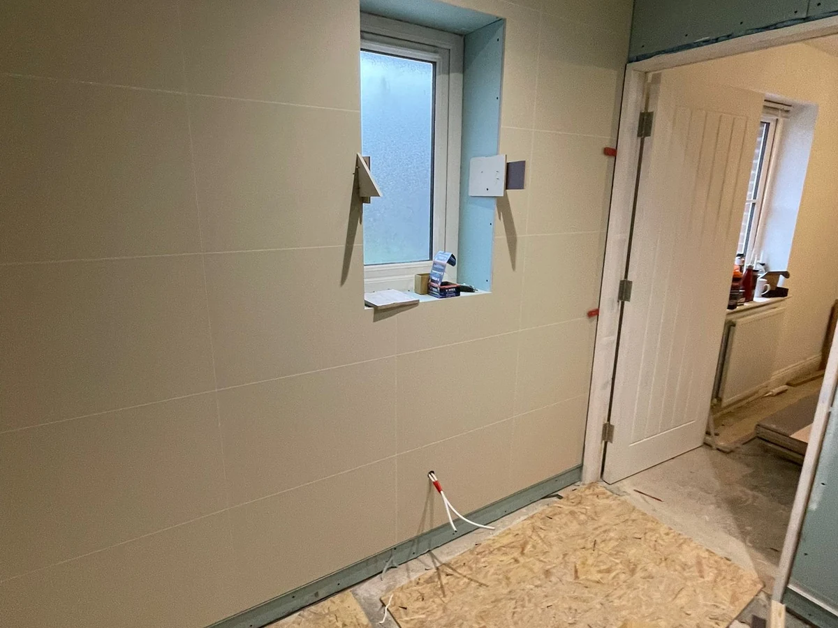 Blue-grey tiled bathroom room view with window and door in Swansea
