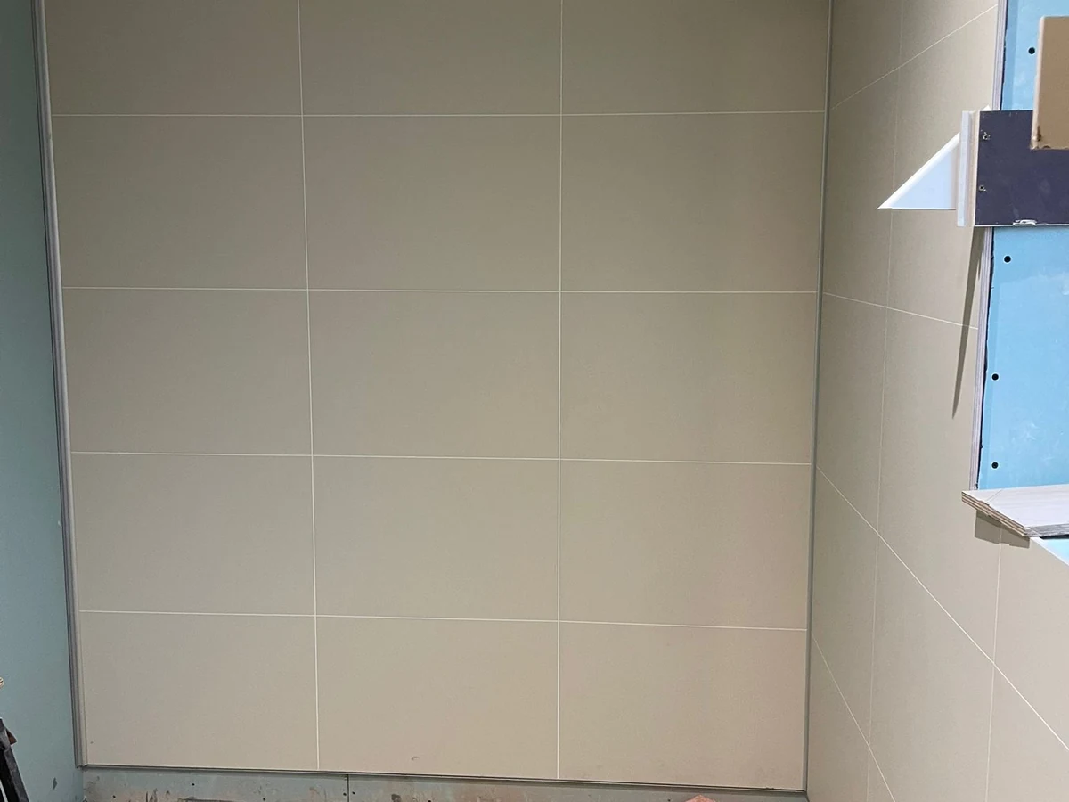 Large format beige wall tiles fitted floor to ceiling during bathroom renovation in Swansea by Daffodil Carpentry